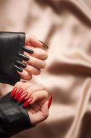 manos de una joven con manicura negra y roja en las uñas foto