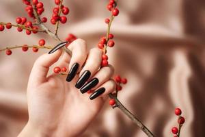 manos de una joven con manicura negra en las uñas foto