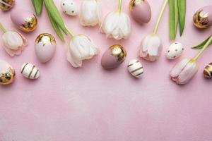 Pascua de Resurrección dorado huevos y rosado tulipanes en rosado antecedentes. foto
