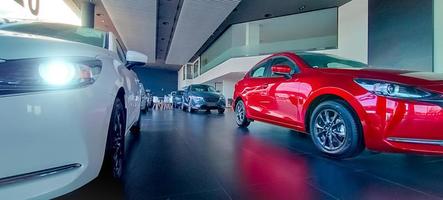 Car parked in luxury showroom. Car dealership office. New red car parked in modern showroom. Auto for sale and rent business concept. Automobile leasing and insurance concept. Car dealer company. photo