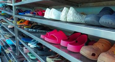 Shoes of workers and visitors in the shoe rack of the factory. Many shoes for men and women are organized on the shoe rack. Footwear in factory concept. Many kinds of shoes, sneakers, and sandals. photo