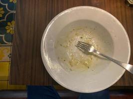 Dirty plate with food leftovers on wooden background, top view photo