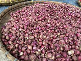 close up of red onion on round wooden tray in traditional market photo