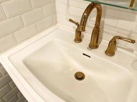 Interior of bathroom with retro classic washbasin and gold faucet. Bathroom interior sink with classic design in luxury hotel. photo