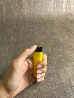 yellow lighter isolated on white background. hand tried to lit yellow lighter. copy space. selected focus photo