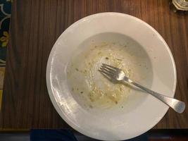 Dirty plate with food leftovers on wooden background, top view photo