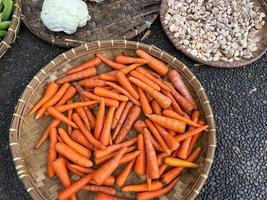 fresco, orgánico y imperfecto zanahorias en redondo bambú bandeja siendo vendido a tradicional mercado foto