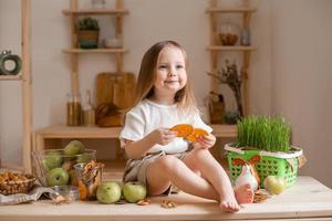 linda pequeño niña come natural pastilla a hogar en un de madera cocina. comida para niños desde natural productos foto