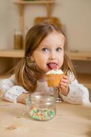 Cute little girl in a cotton dress at home in a wooden kitchen prepares an Easter cake photo