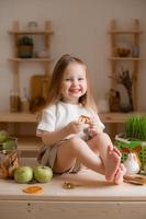 linda pequeño niña come natural pastilla a hogar en un de madera cocina. comida para niños desde natural productos foto