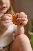 linda pequeño niña come natural pastilla a hogar en un de madera cocina. comida para niños desde natural productos foto