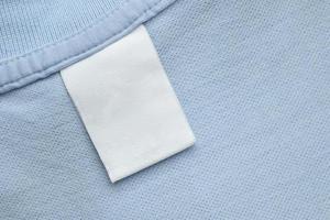 White blank laundry care clothes label on blue shirt fabric background photo