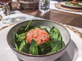 Tuna tartare with salad is served on a table that has been set up. photo