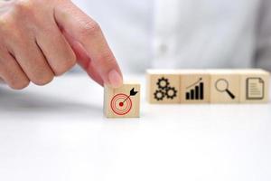 Hand holding a wooden block cube with target icon symbol. Business strategy and target of business. photo