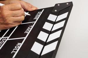 Focus the hand is holding clapperboard or movie slate black color and marker pen. Cinema industry concept. photo