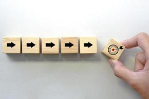 Hand holding a wooden block cube with target icon symbol. Business strategy and target of business. photo