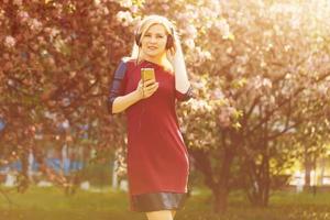 Portrait of young beautiful woman with headphones listening music. Outdoors. Urban concept. photo