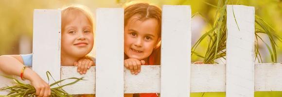Two beautiful young girls in the garden fence photo