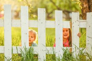 Two beautiful young girls in the garden fence photo