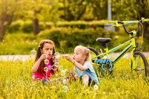 Two children in the park blowing soap bubbles and having fun photo
