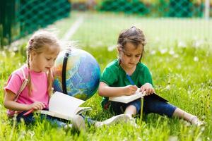 Concept - education. Back to school. Two cheerful Caucasian girls schoolgirls with a globe, happy to be returning home after class in class photo