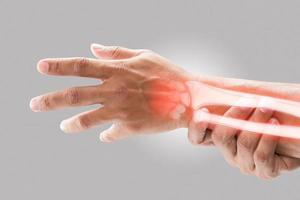 A man massaging painful wrist on a gray background. Pain concept. Osteoporosis photo