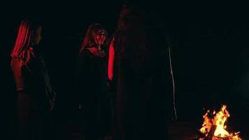 un grupo de personas vestido en negro es ejecutando un satánico ritual en frente de un hoguera video