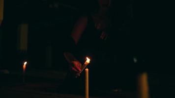 een vrouw in zwart is verlichting een kaars dat gaat uit in de donker voordat het uitvoeren van een elke avond duivel aanbidden video