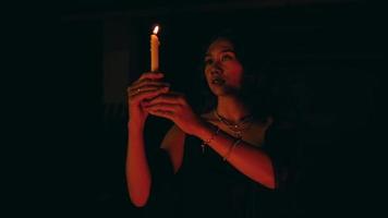 a woman performs a satanic ritual movement with a lit candle in the dark video