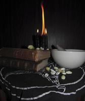 ritual todavía vida de negro magia. negro velas, libros, cauri conchas, mortero y majadero, anillo en un oscuro antecedentes foto