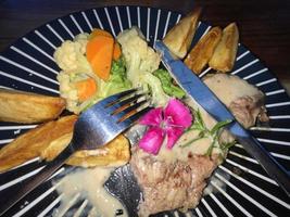 Juicy beef steak with salad and potato wedges along with pepper corn sauce photo