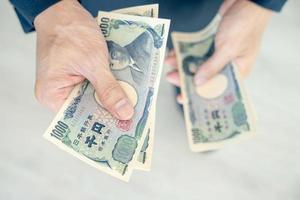 japonés yen dinero. cerca arriba de el japonés yen en mano. moneda de Japón ese es usado a cambiar, comprar, vender, acumular, invertir, financiero, intercambiar tasa, valor, contabilidad, internacional intercambiar foto