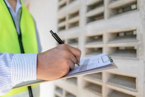 el inspector o ingeniero está inspeccionando la construcción y el aseguramiento de la calidad de la nueva casa usando una lista de verificación. ingenieros o arquitectos o contratistas trabajan para construir la casa antes de entregársela al propietario foto