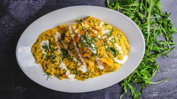 Coconut chicken curry marinade with sauce and coriander on a white plate black background. photo
