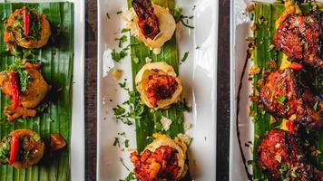 Asian spicy tuna tartare with potato and fuchka also with other dishes like chicken dish and vegetable fuchka, sprinkle coriander leaves, served on a white plate and banana leaves. photo