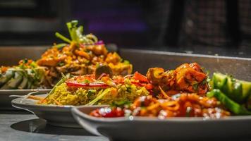 A table topped with lots of different types of food, colorful dramatic lighting, close up shot from the side. photo
