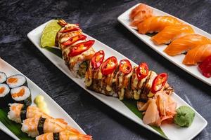 Plates filled with different types of sushi, Saki Sushi, Kraken Sushi, Salmon jhow sushi, Nigiri sushi, and Salmon hosomaki sushi on a black table. photo