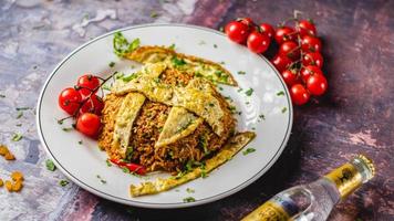 Spicy Indian chicken biriyani omelet served with coriander on a white plate and red tomatoes on the side. photo
