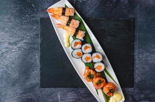 Salmon jhow sushi, Nigiri sushi, and Salmon hosomaki sushi on a black table with a black mate under the plate. photo