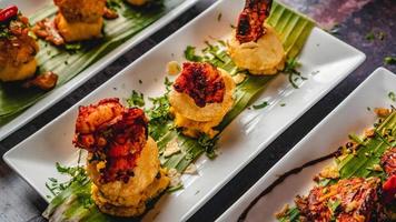 asiático picante atún tartar con patata y fucka además con otro platos, espolvorear cilantro hojas, servido en un blanco plato y plátano hojas. foto