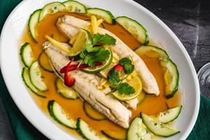 A close-up of a plate with steamed sea bream, Steamed Salmon Recipe, swirling silverfish, cucumber. photo