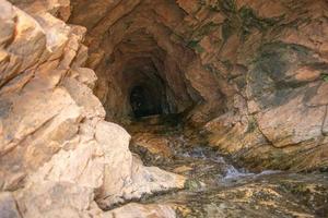 cueva en rocoso montaña con río en el piso foto