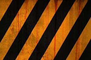 Concrete wall covered with rust stains and paint in yellow and black stripe photo
