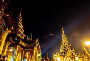 las pagodas doradas y los mondops se iluminan a la luz de la noche foto