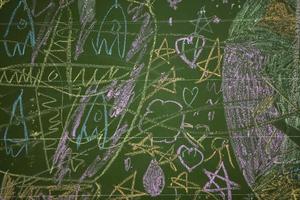 Drawings of children with chalk on a school green board. photo