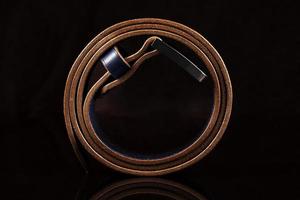 Twisted brown leather belt on a dark background. photo