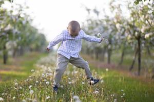 A happy child in a blooming spring garden plays, jumps, he is in a good mood. photo