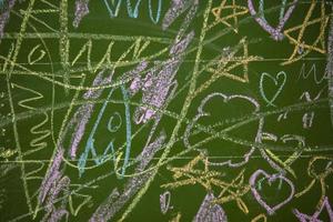 Drawings of children with chalk on a school green board. photo