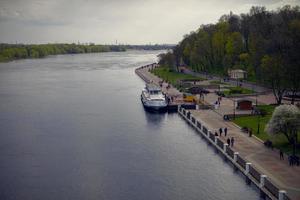 ciudad terraplén de el río con un Embarcacion y peatones parque zona de el ciudad. foto