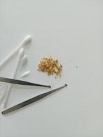 Earwax and two ear pick tools and cotton swabs On the light blue table top photo